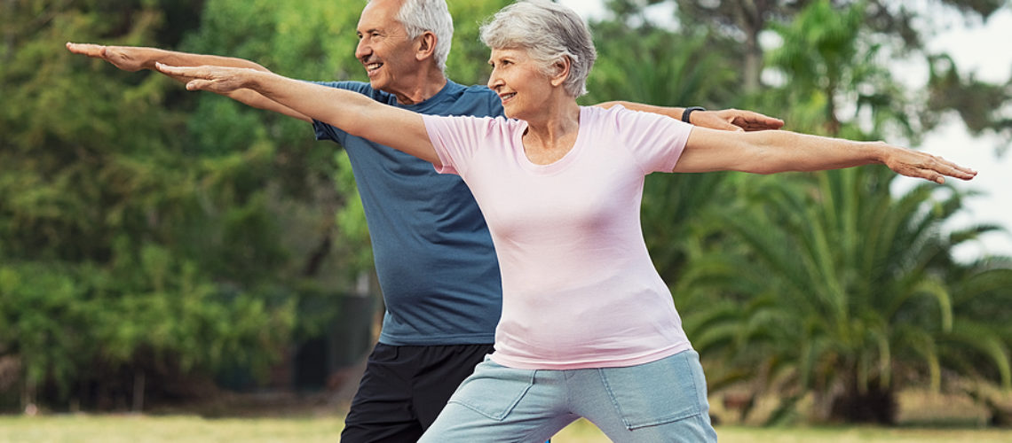 Senior couple doing sport and physical exercises outdoor. Active senior man and elderly woman doing workout at park. Aged couple doing their stretches in the park.